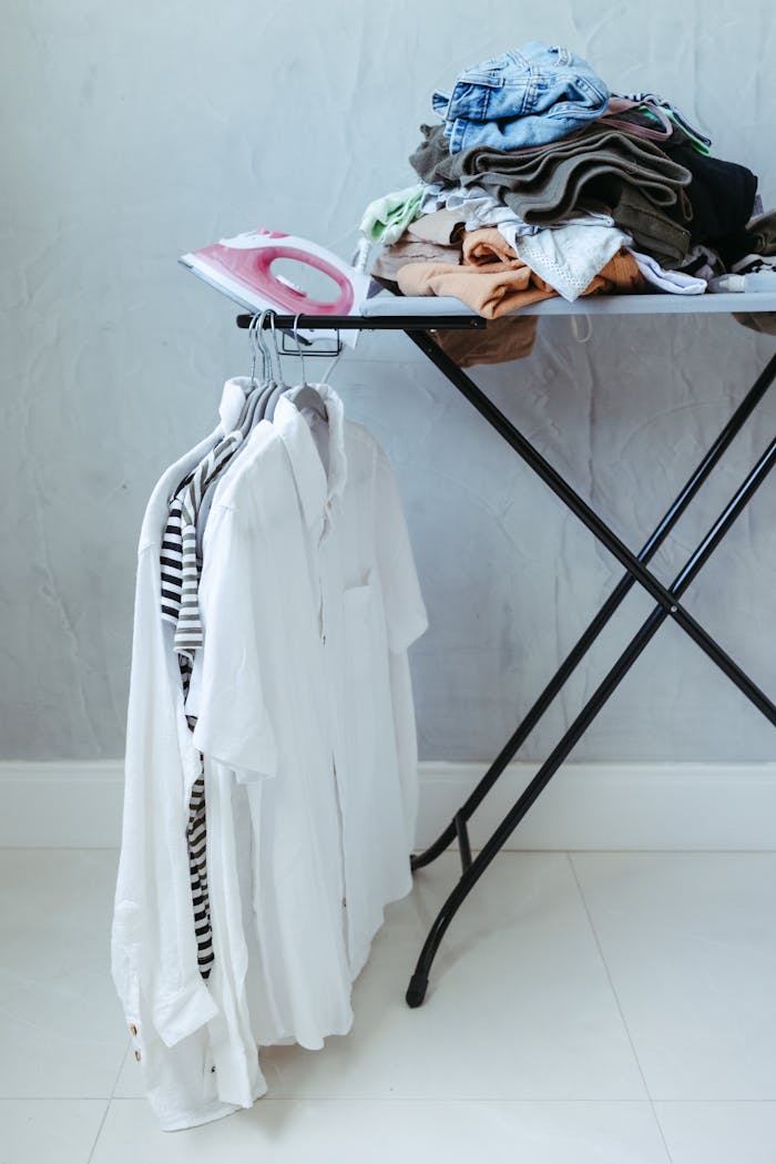A neatly organized ironing board with clothes and an iron in a bright minimalist room.
