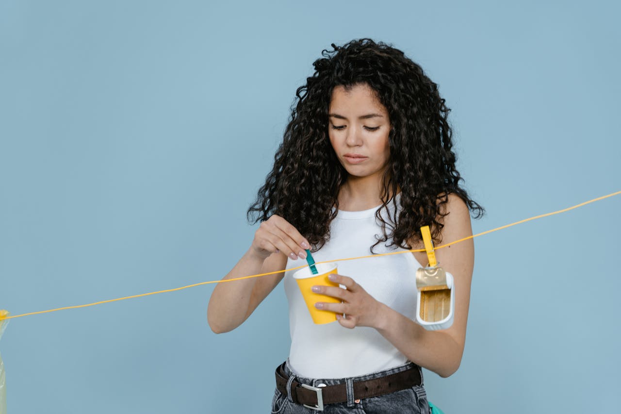 Young woman engaged in creative painting in a studio. Minimalist setup with light blue background.
