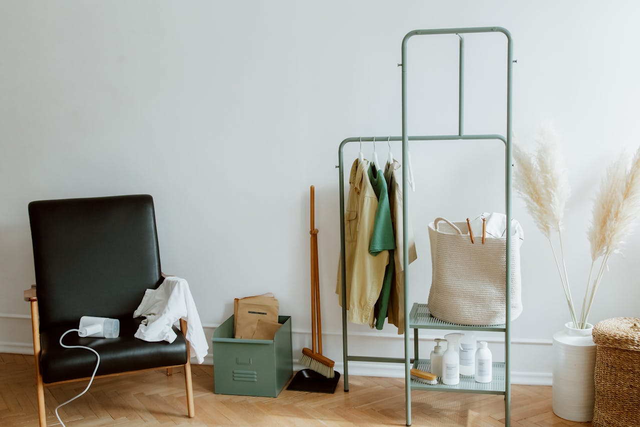 A cozy minimalist home corner with a black leather chair and clothing rack.